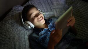 Boy streaming movie on tablet while laying on bed